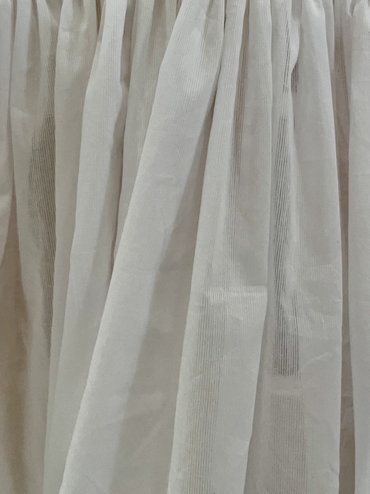 A gathered length of semi-sheer cotton with fine white stripes.