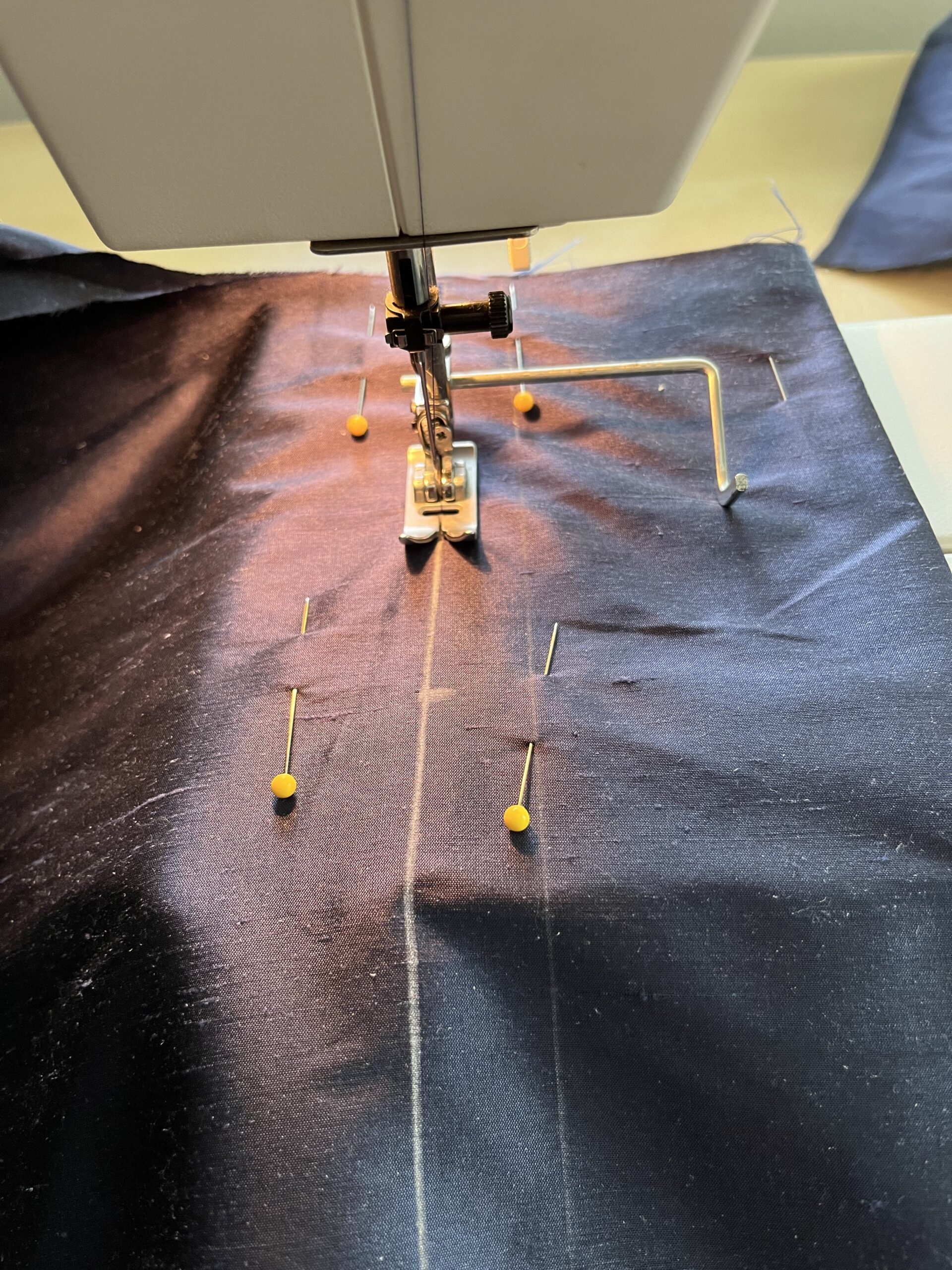 a back pleat being sewn by machine on purple silk
