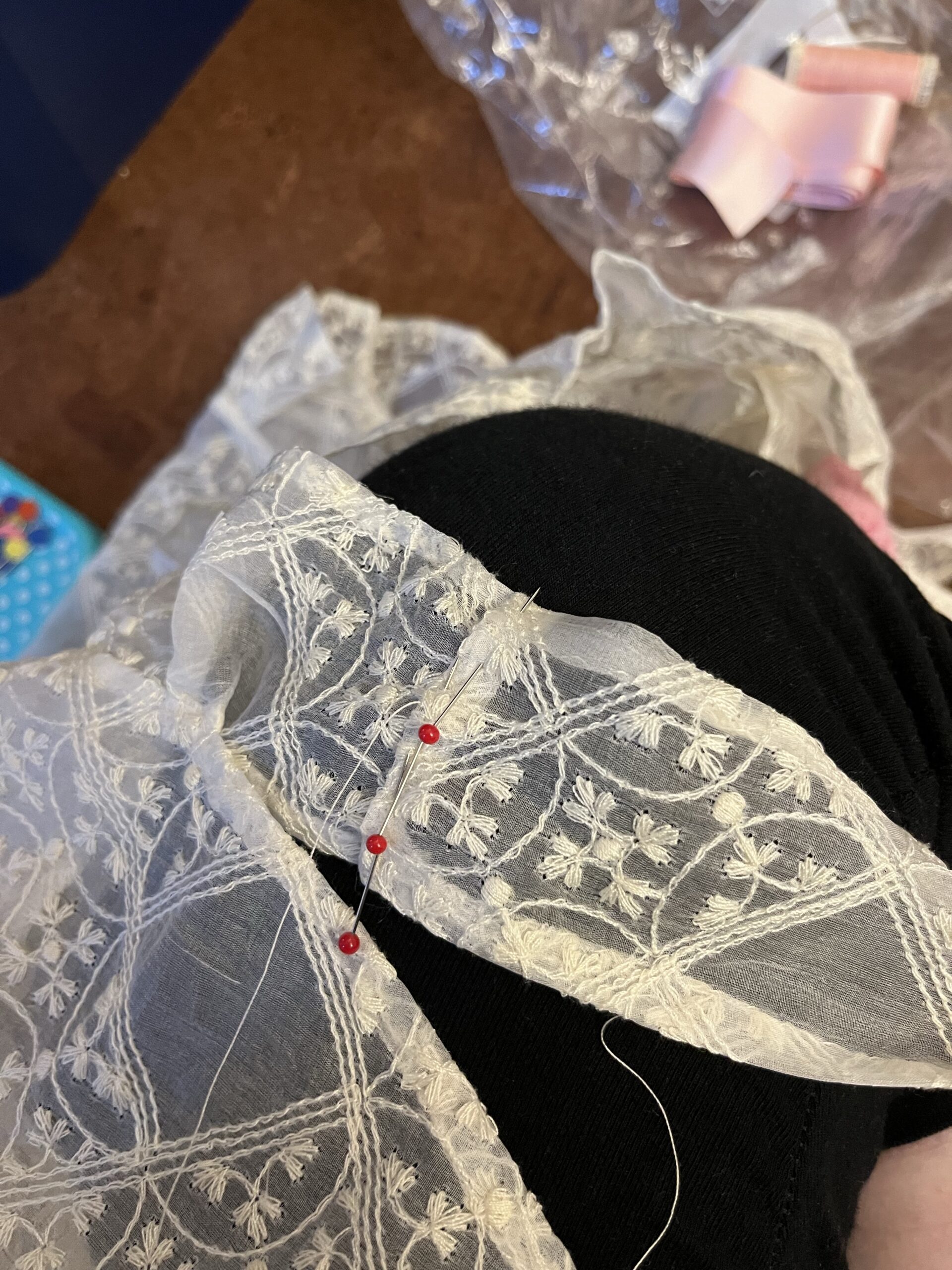 A length of silk trim is being pinned to another length of silk trim