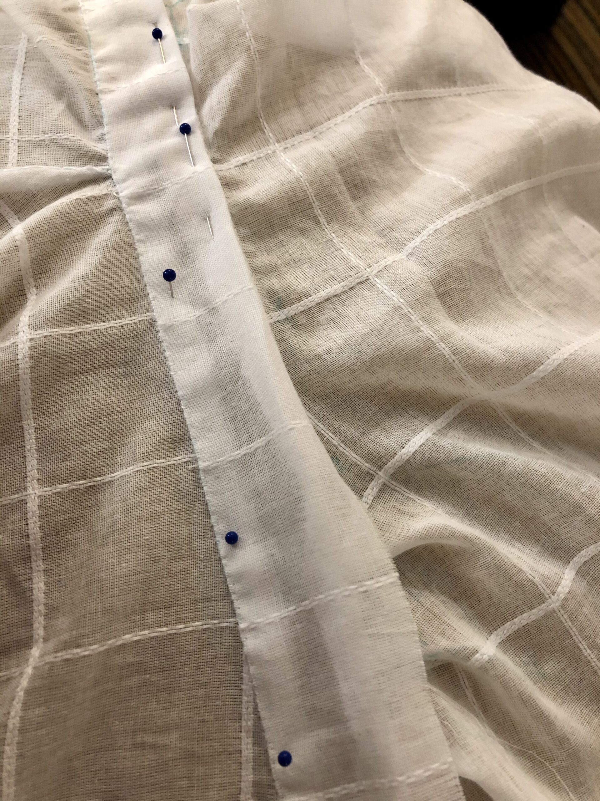 A close-up of white cross-barred cotton being stitched to a neckband