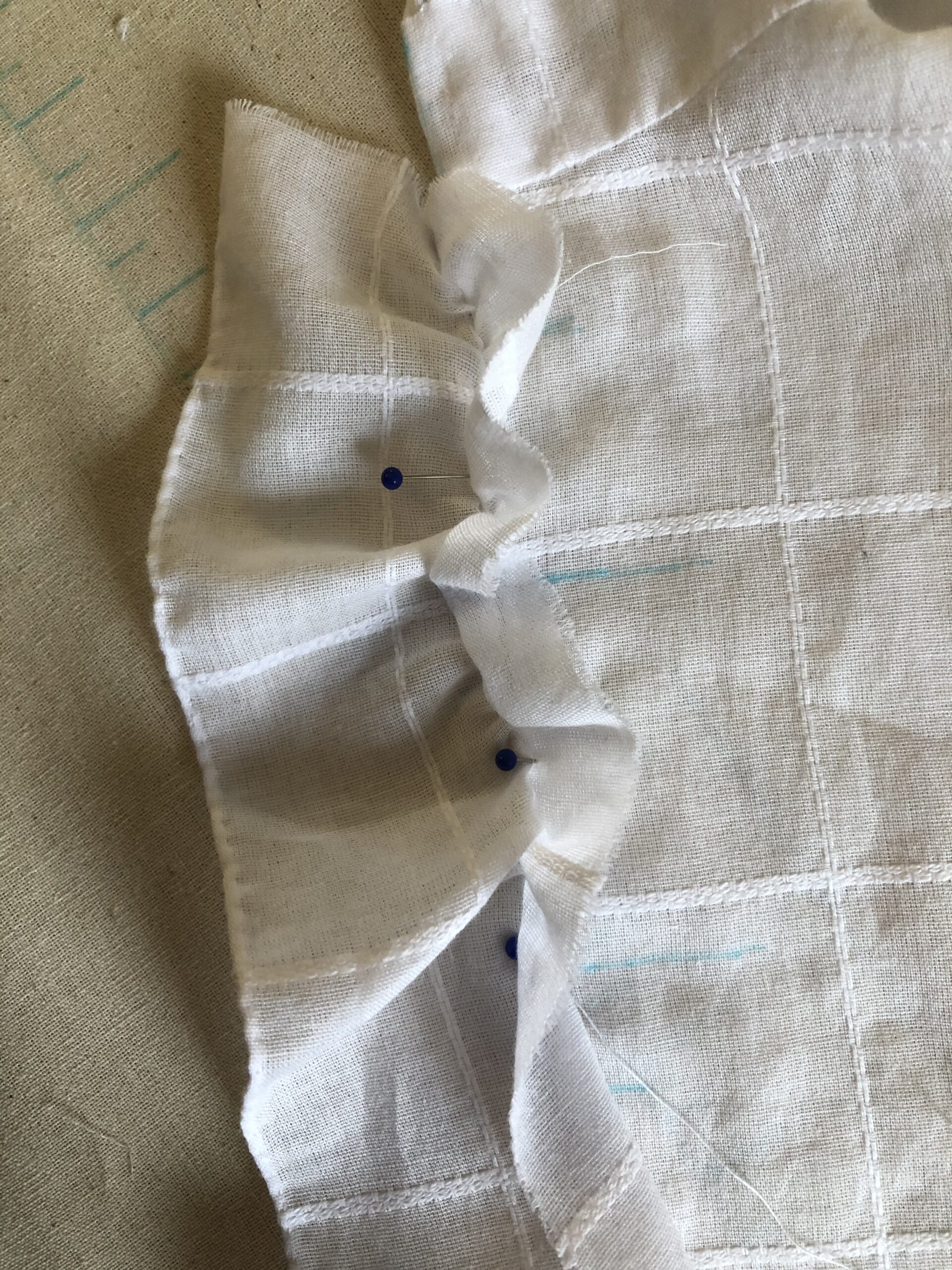 close-up of a ruffle punned to a white cotton mantelet.
