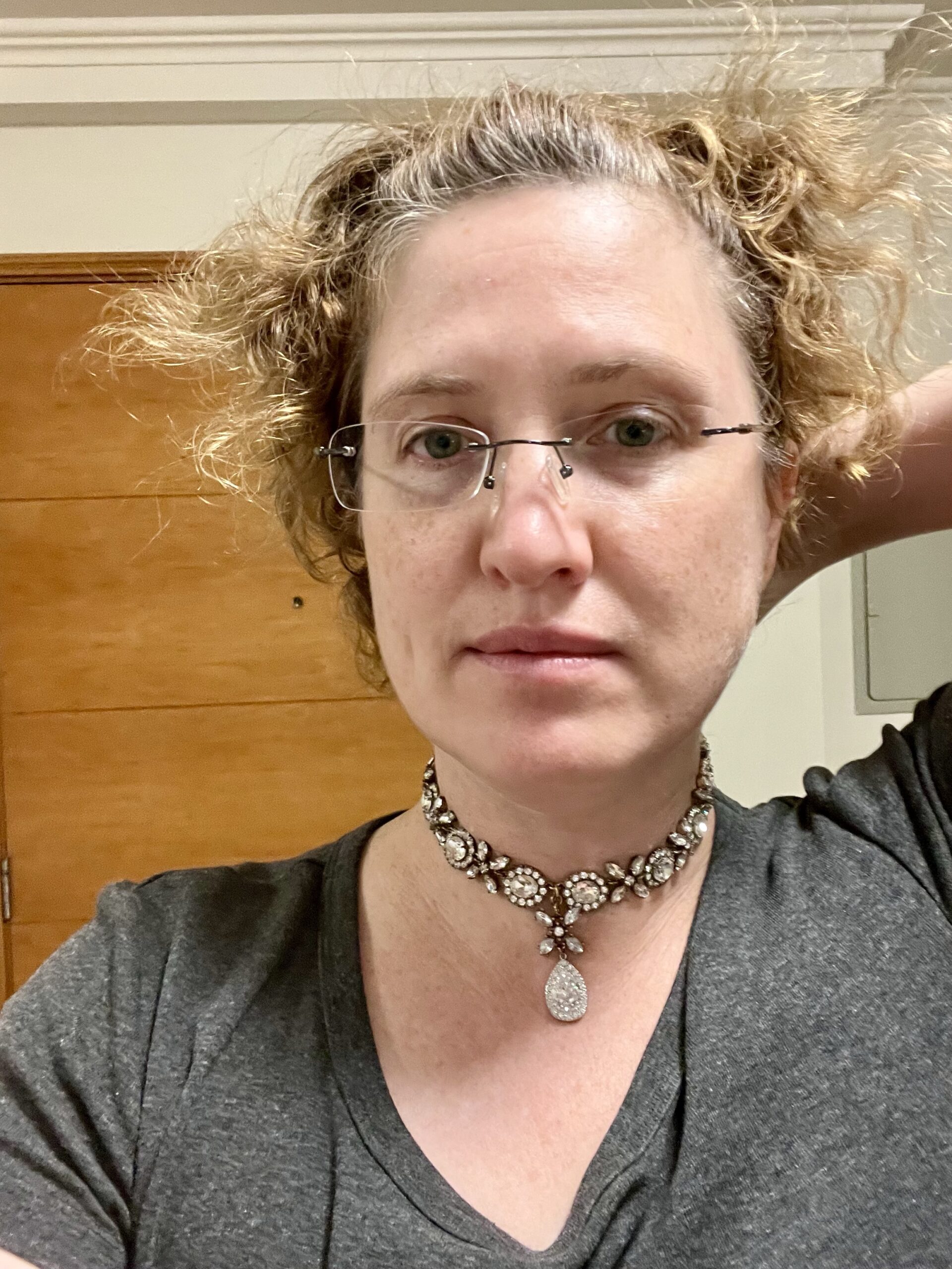 A woman faces the camera. She has light frizzy hair and is wearing glasses and a Georgian paste necklace with short pendant drop