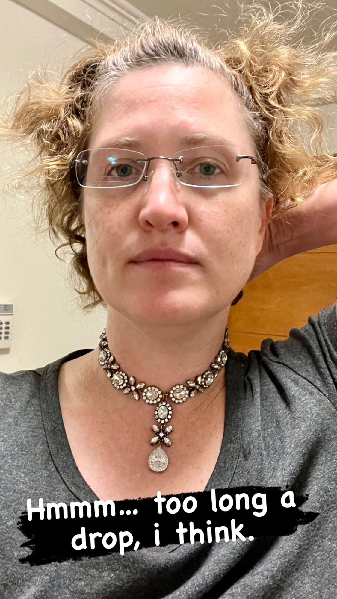 A woman faces the camera. She has light frizzy hair and is wearing glasses and a Georgian paste necklace with long pendant drop