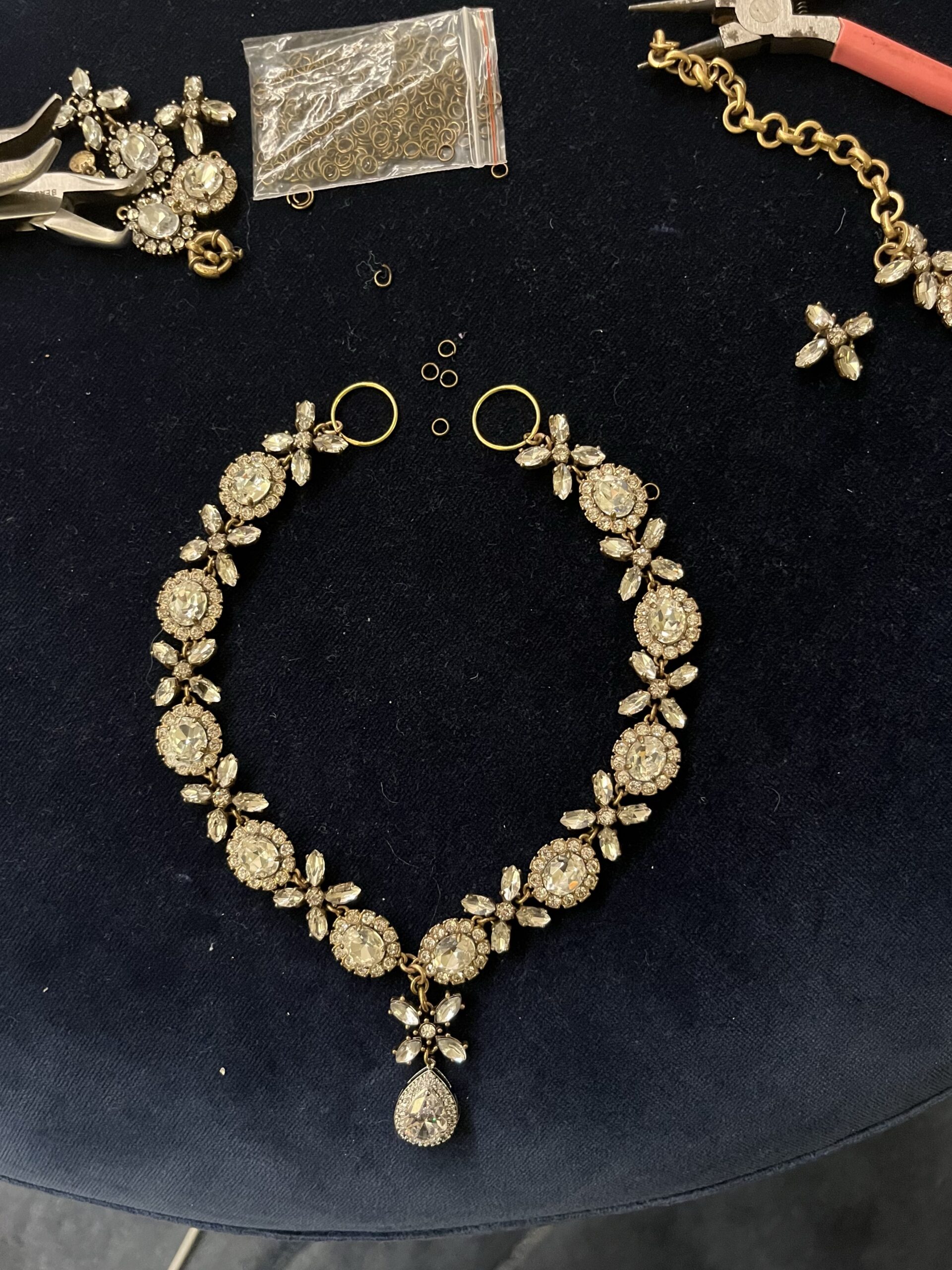 A hug-and kiss rhinestone necklace with a pendant drop likes on a bed of blue velvet