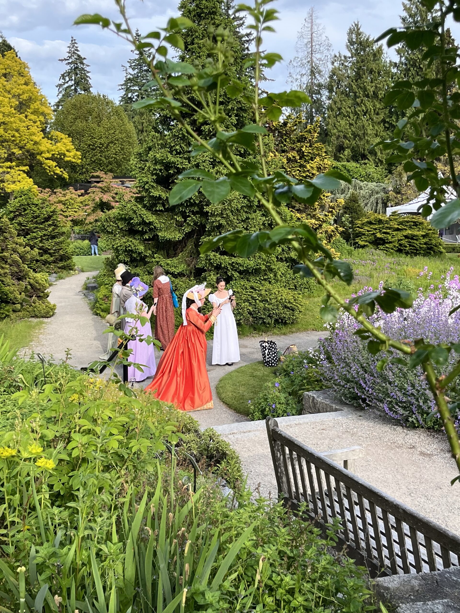 a group of people in regency clothing pose in a garden