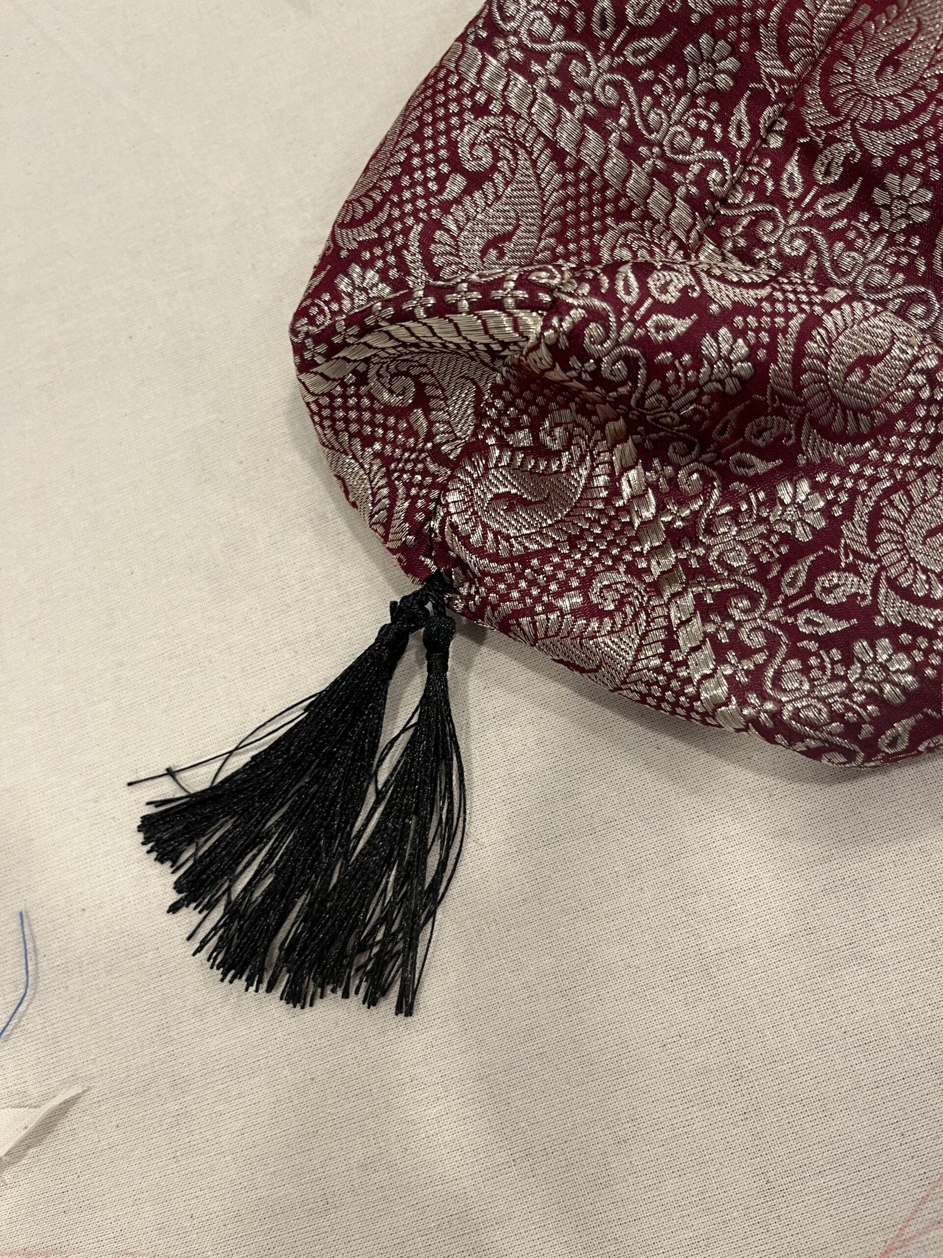 a bundle of black tassel stems at the bottom of a red and silver reticule