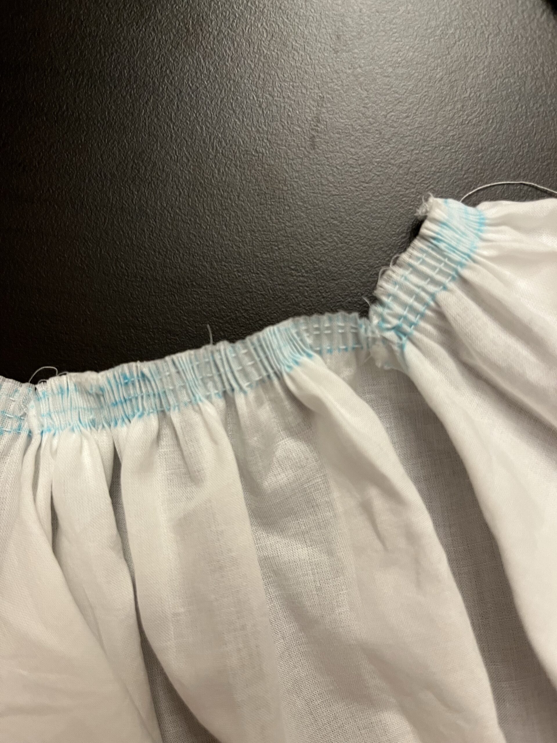 Stroked gathers, marked in blue, being spread out along the neckline of a 1790s chemisette