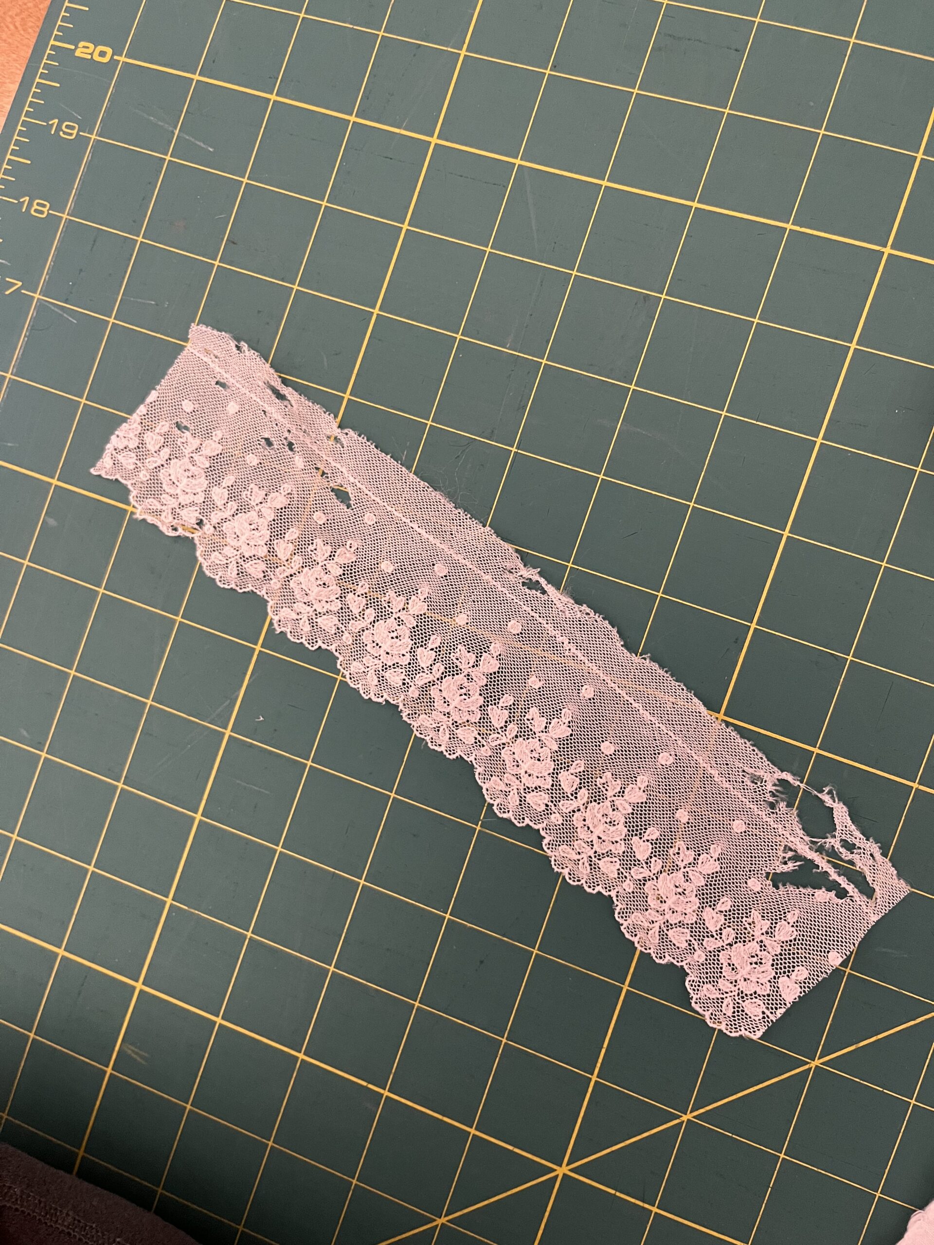 A short piece of white cotton lace with holes in it