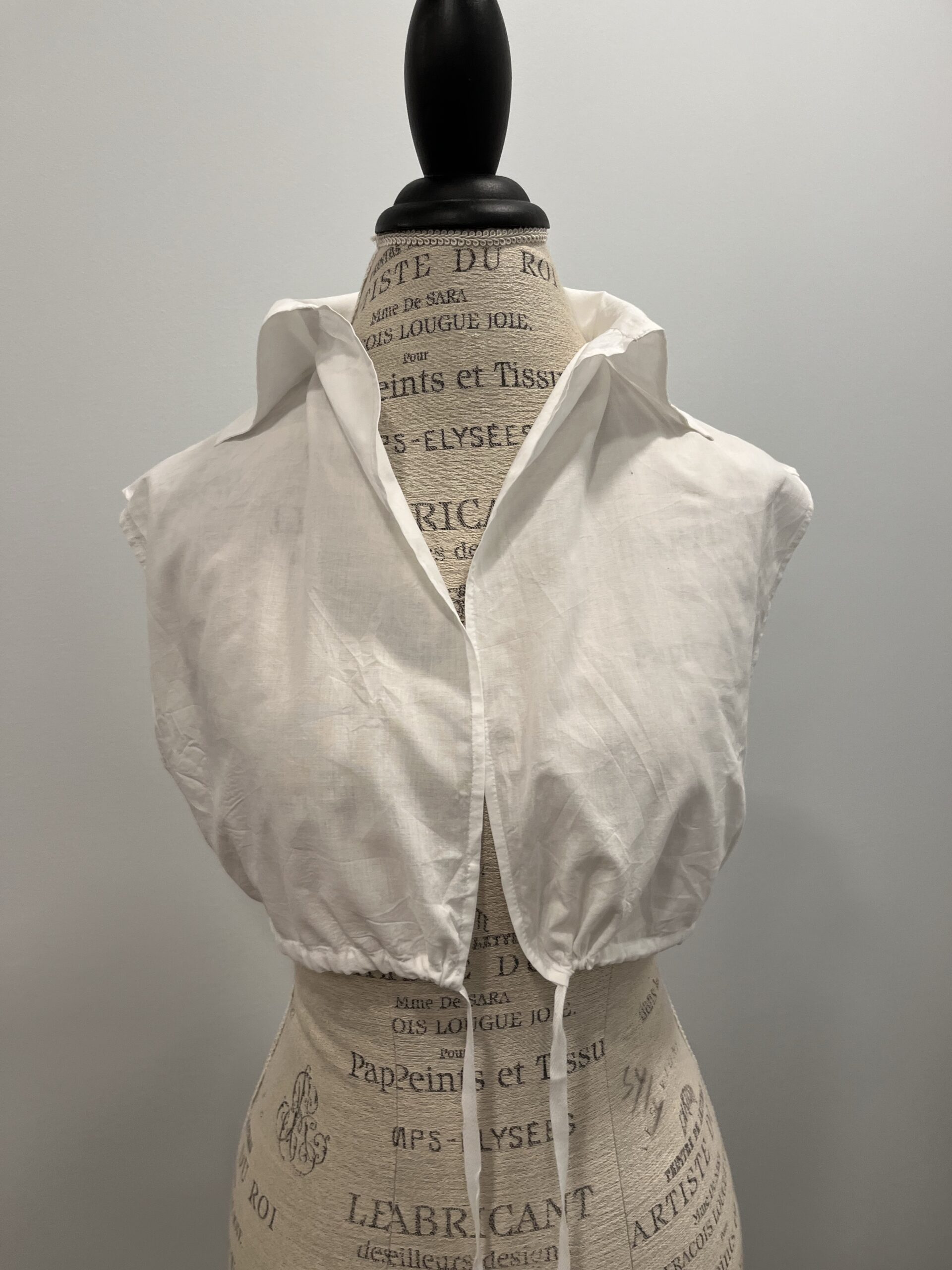 A front view of a white 1790s chemisette mounted on a mannequin