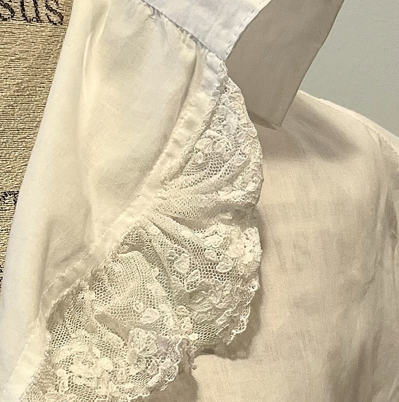 view of the end of a piece of lace stitched and gathered to the front edge of a chemisette