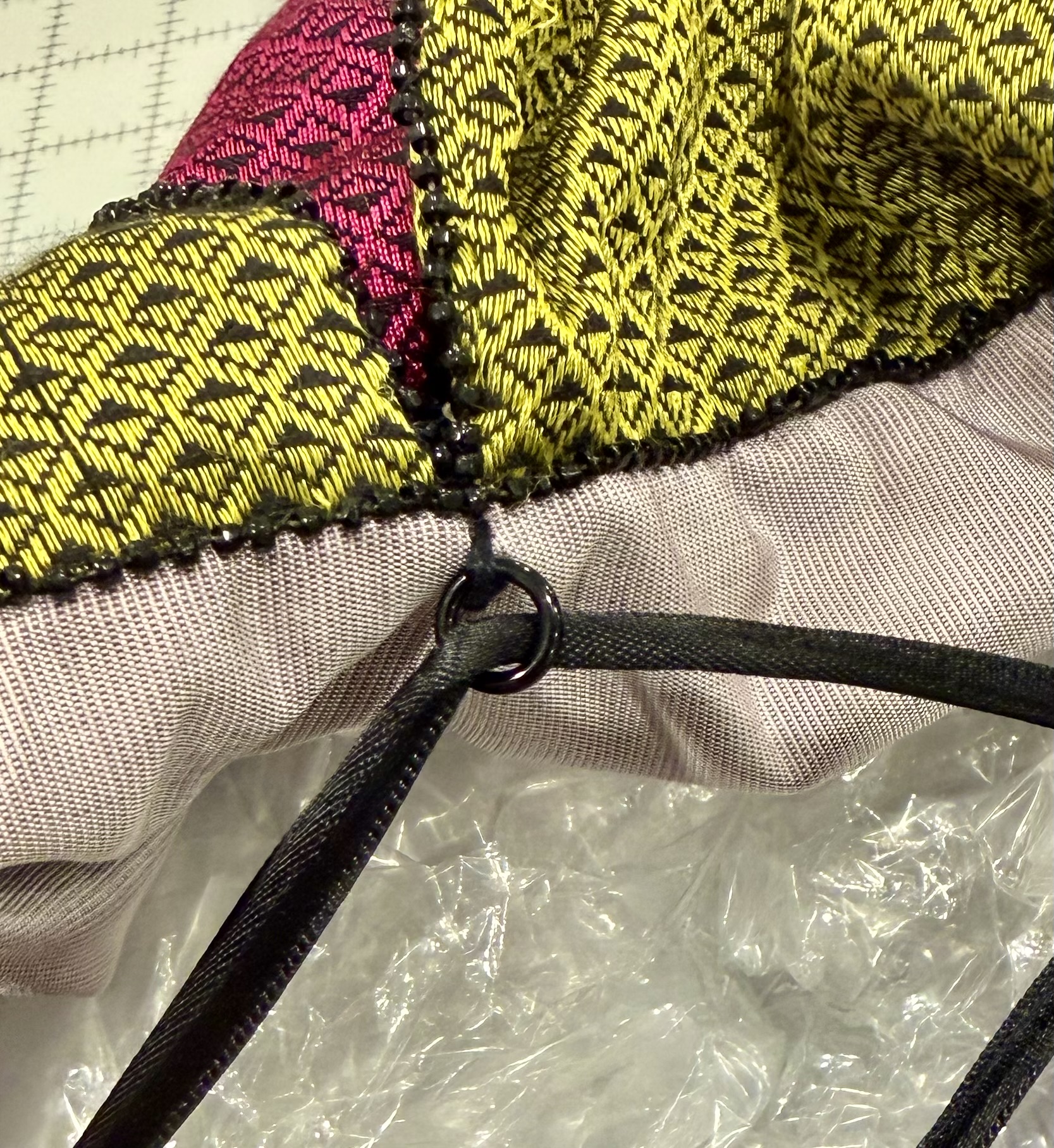 A small metal ring is threaded with a black satin ribbon