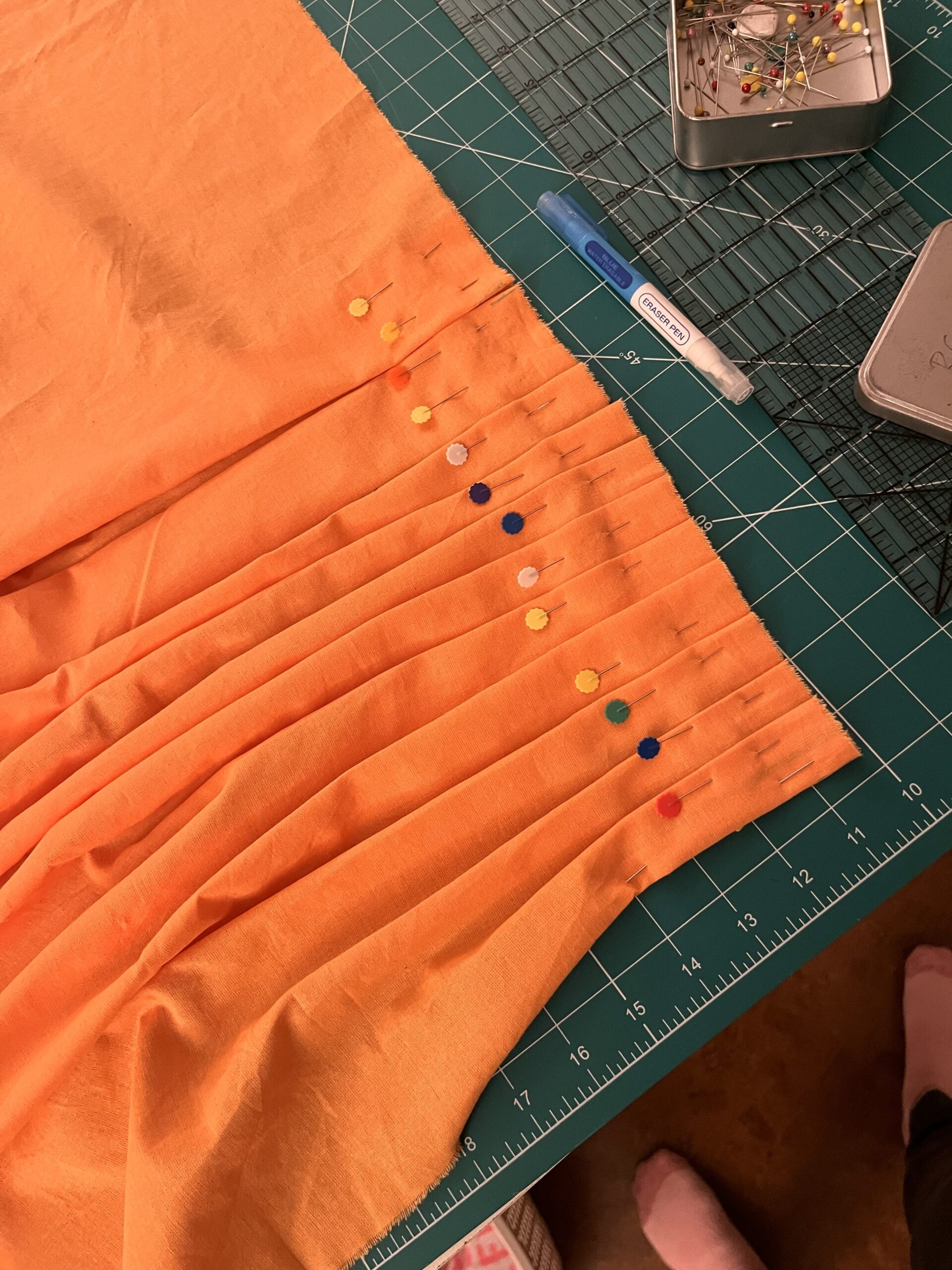 An orange 18th century petticoat back being pleated