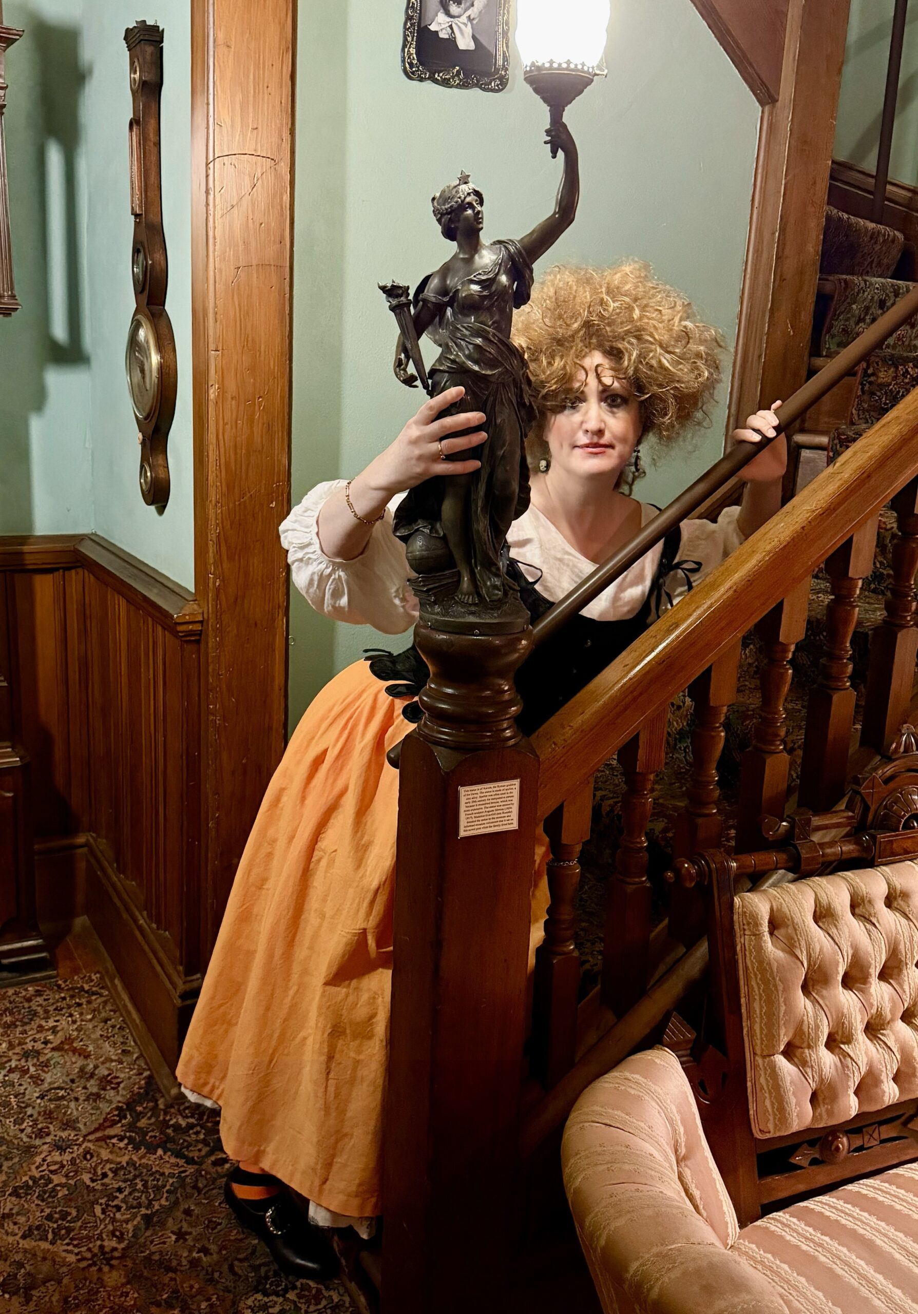 a witchy halloween wench peeps coyly at the camera around a newel post
