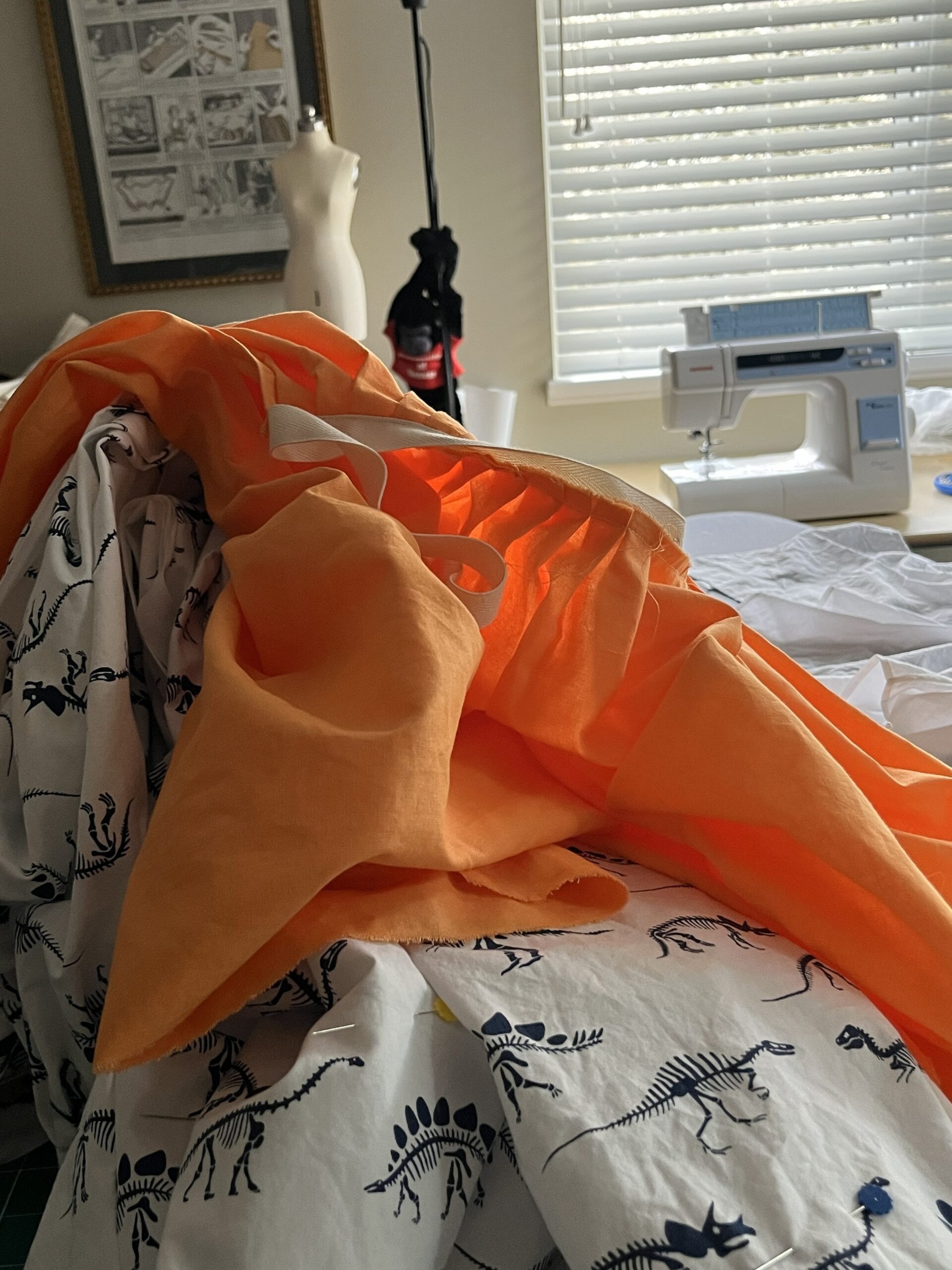 Orange and white petticoats piled beside a sewing machine