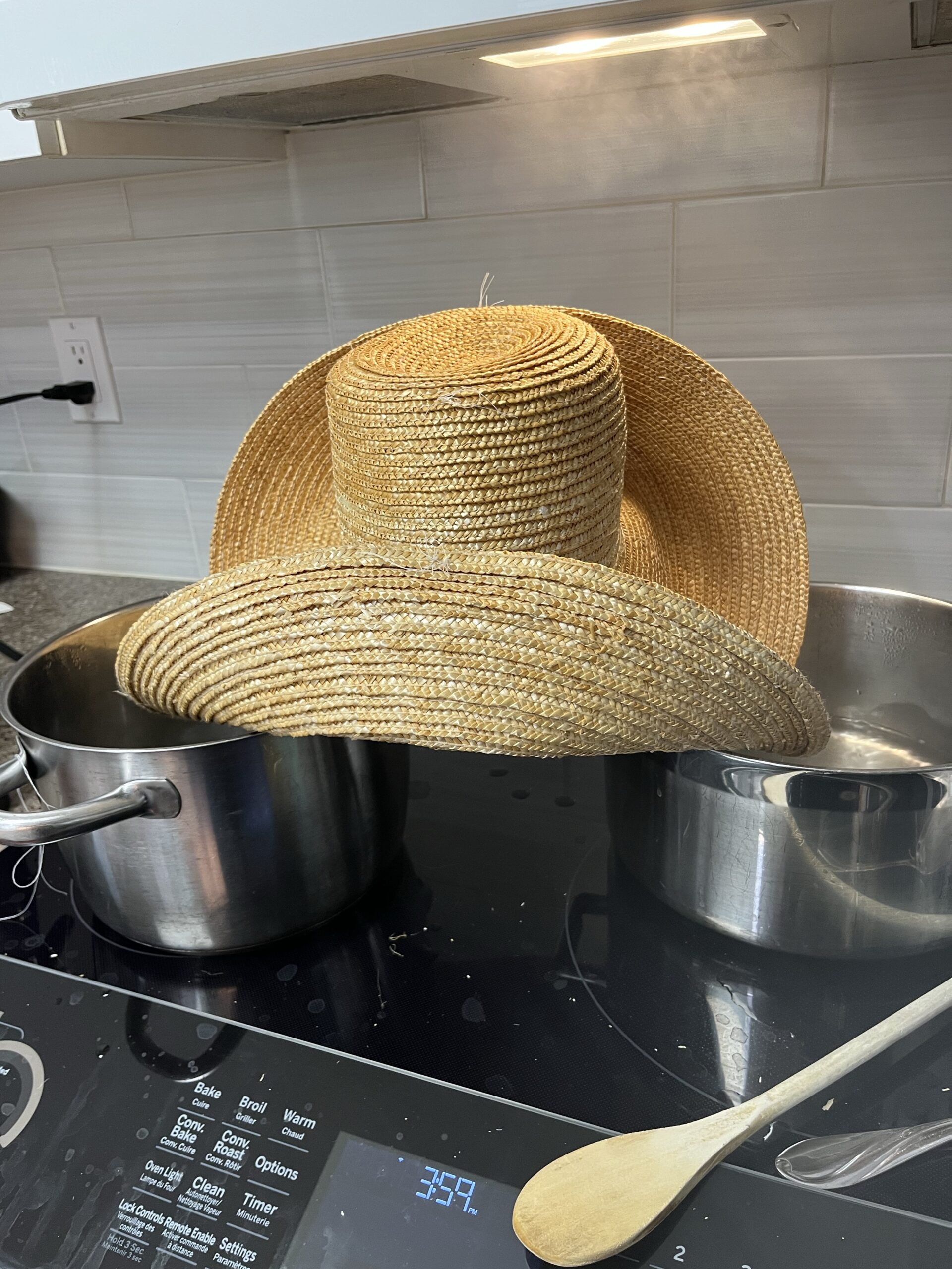 tall crowned straw hat sitting on top of a pot on a stove