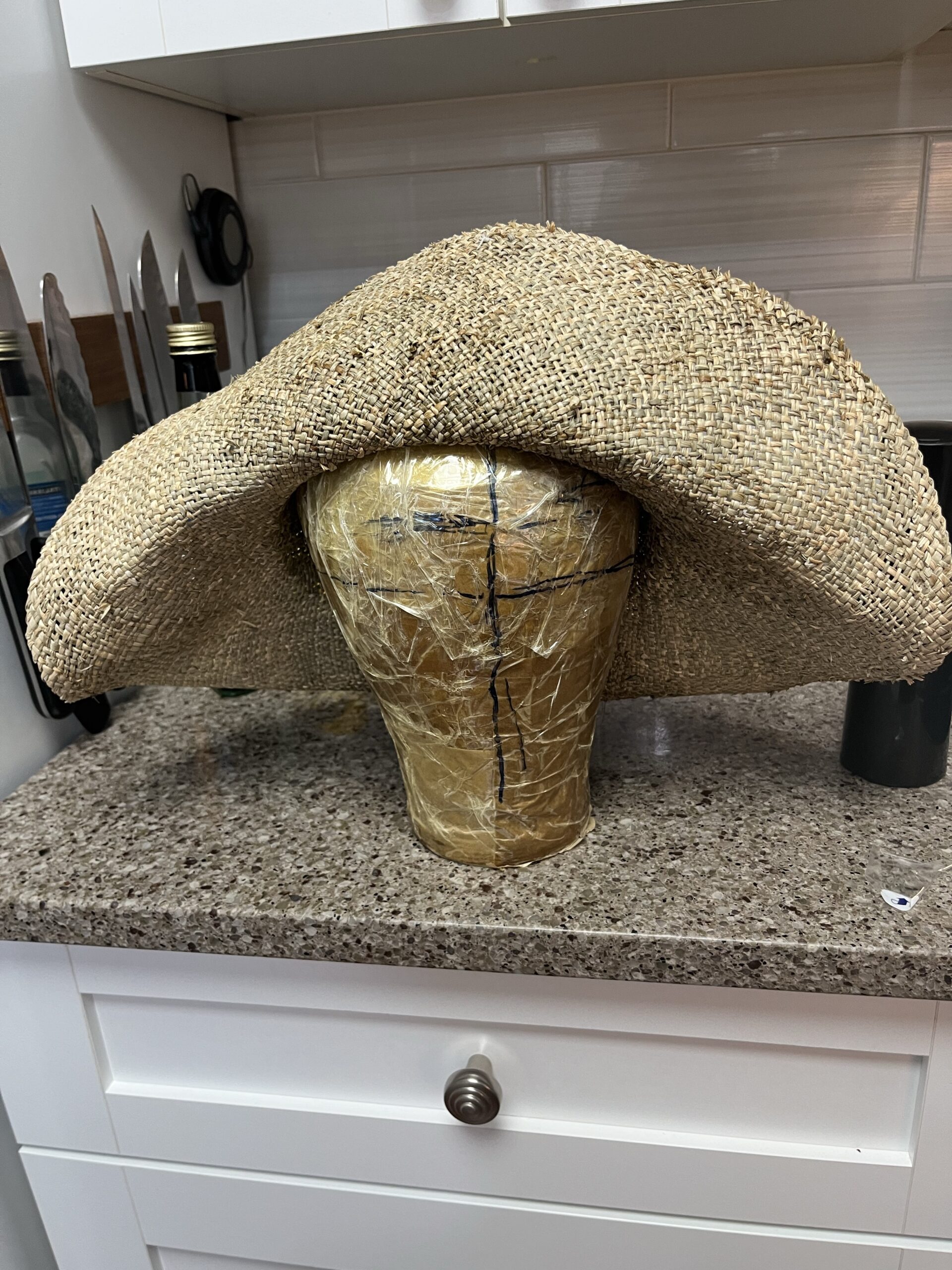 a collapsed seagrass hat blank droops on a wig block