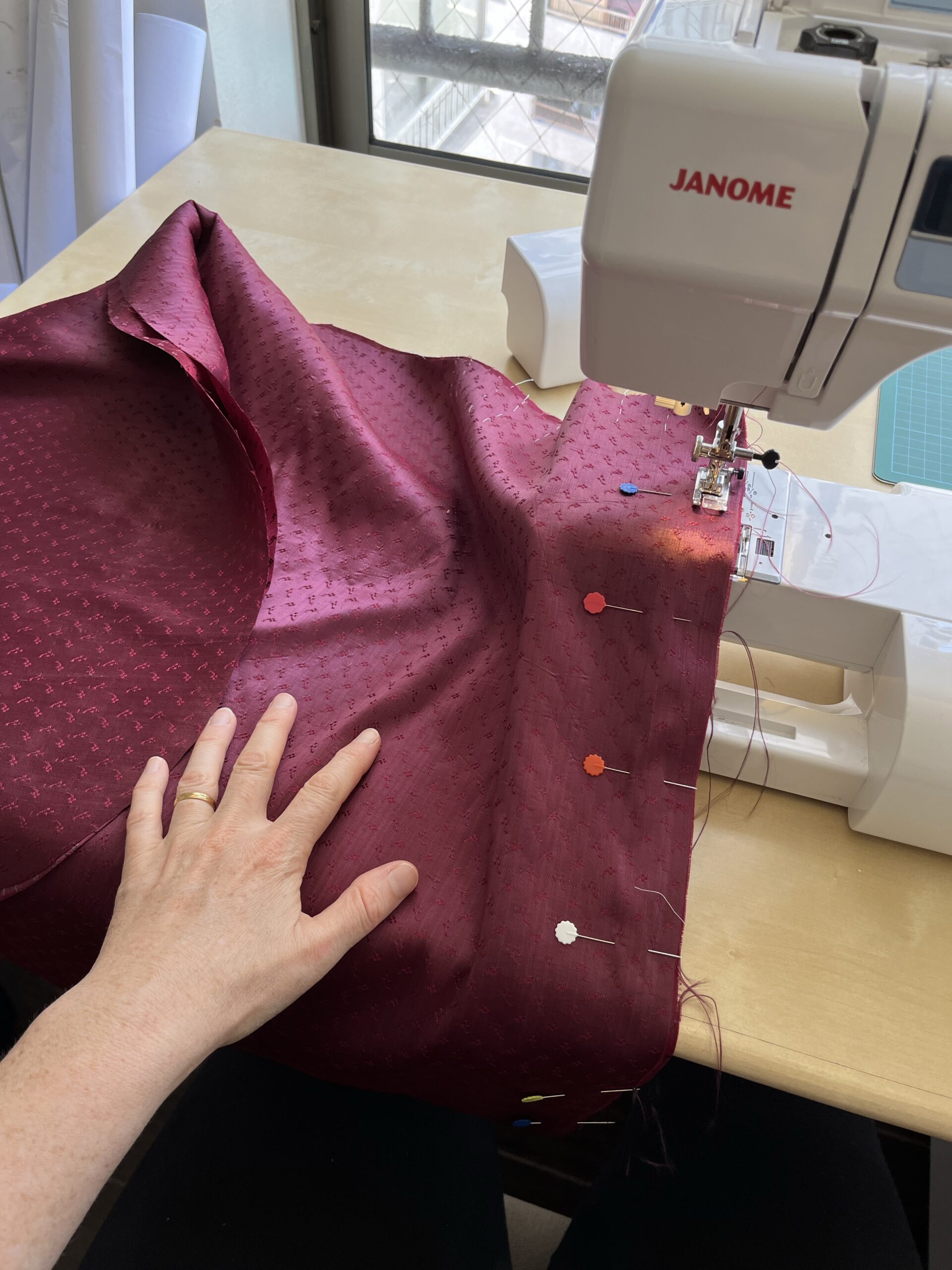 two pieces of red silk being sewn together by machine