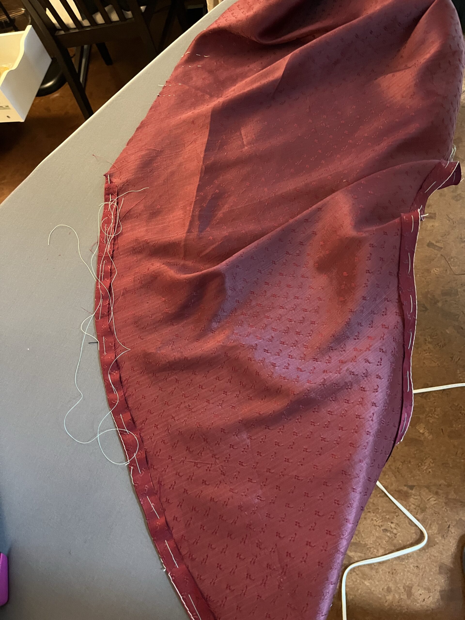 Seam allowances being folded inward on red silk