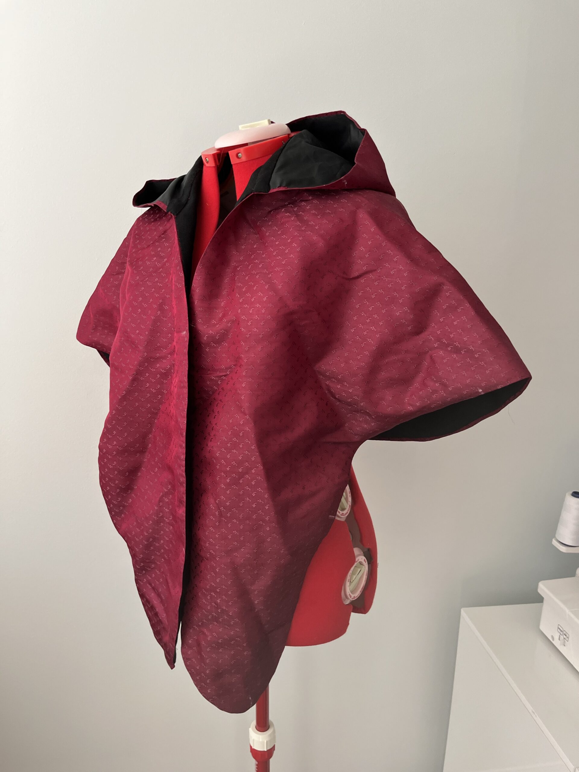 An untrimmed Scroop Charlotte Mantle mounted on a red sewing mannequin