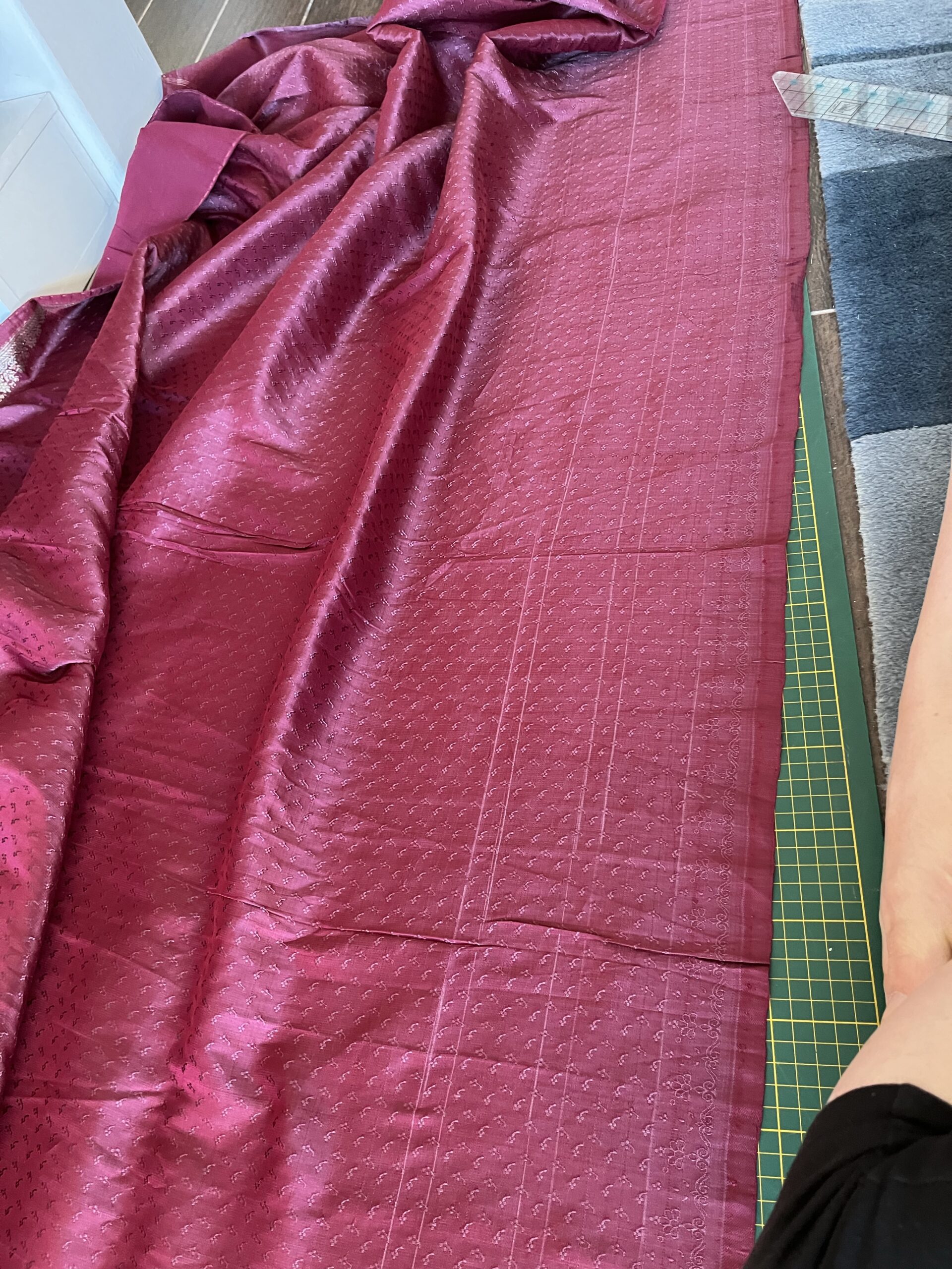 A figured burgundy silk saree with cutting lines drawn in chalk