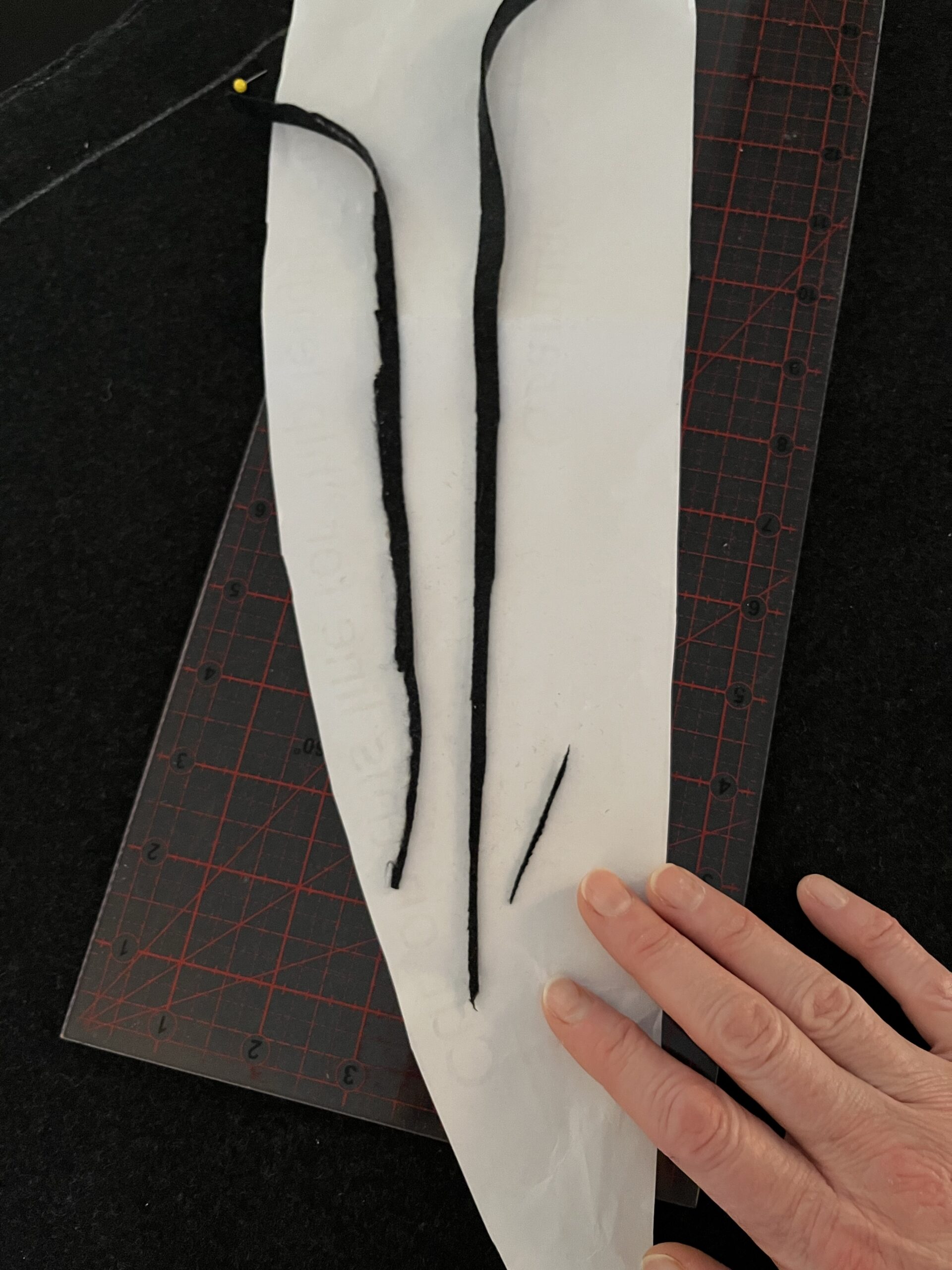 skinny scraps of grey wool lying on white paper