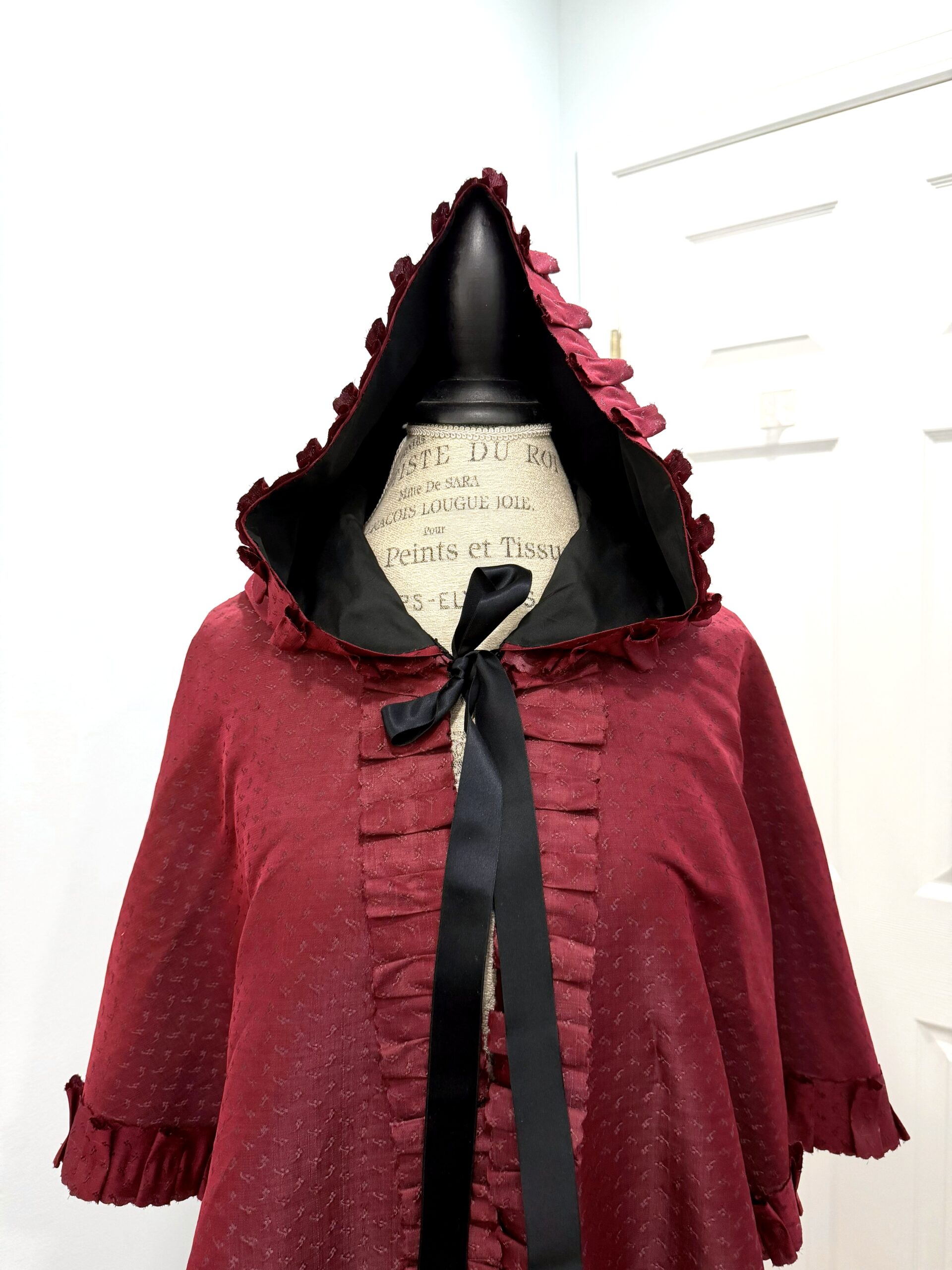 front view of the hood of the Scroop Charlotte Mantle sewn from figured burgundy silk