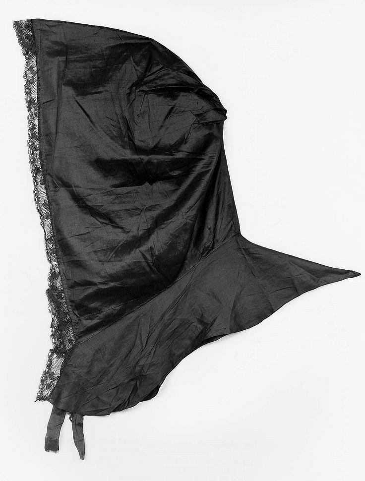 A black silk taffeta hood, lying on its side. the front edge is trimmed with black lace