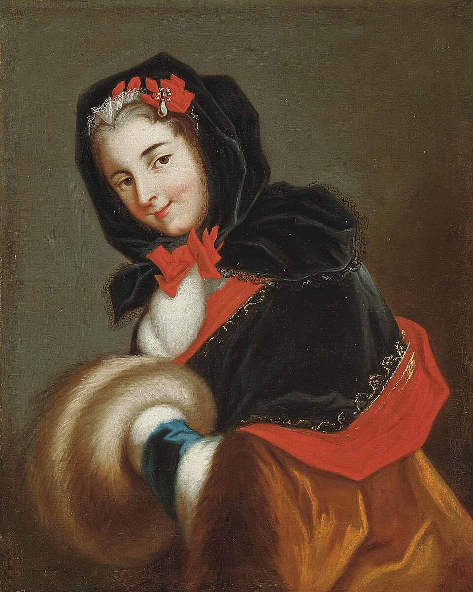 Half portrait of a woman dressed in a brown pelisse with a black hood, carrying a large brown fur muff and everything she is wearing trimmed with red bows