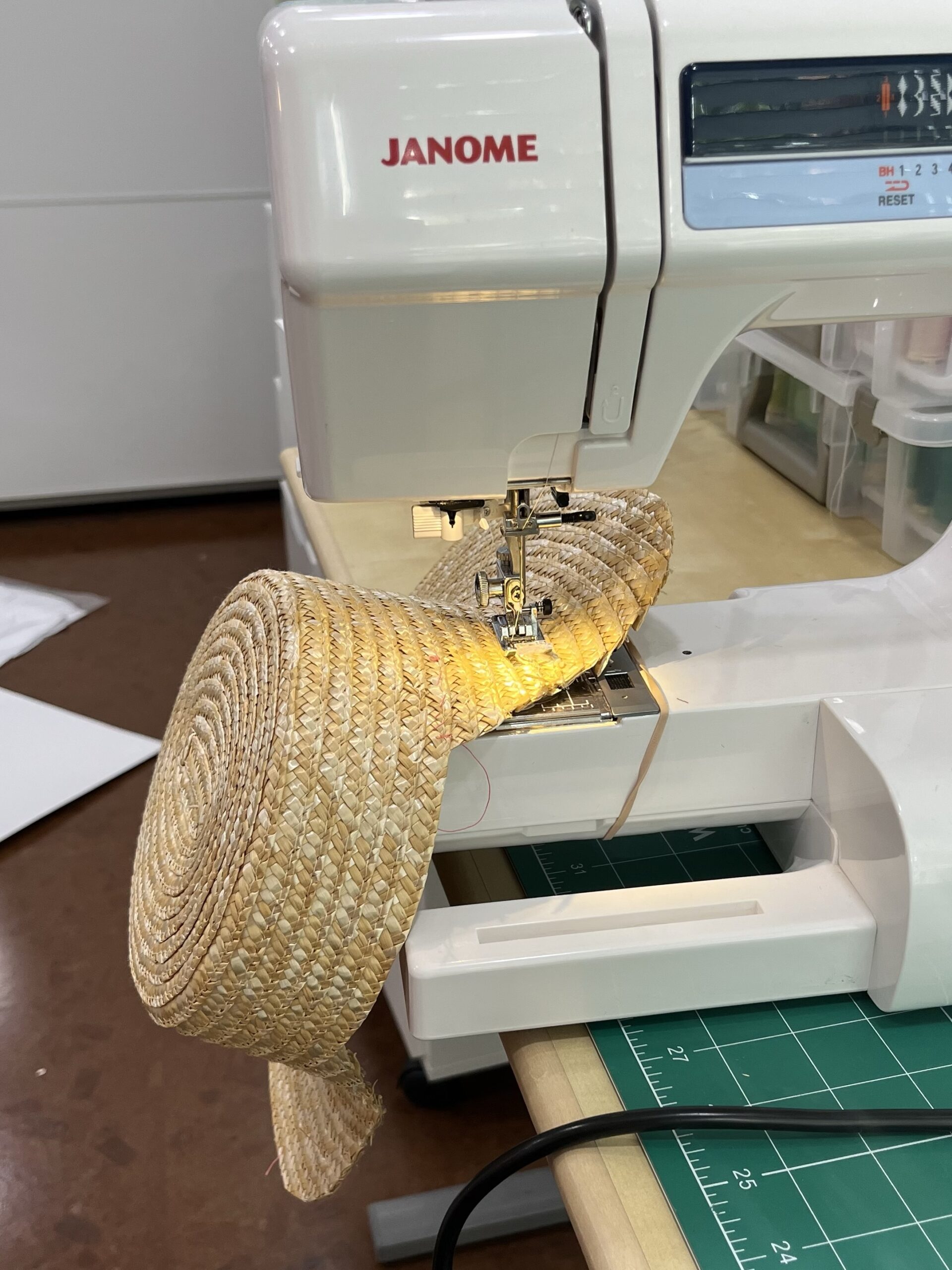a straw hat with a chunk cut out of it has been wedged under a sewing machine needle