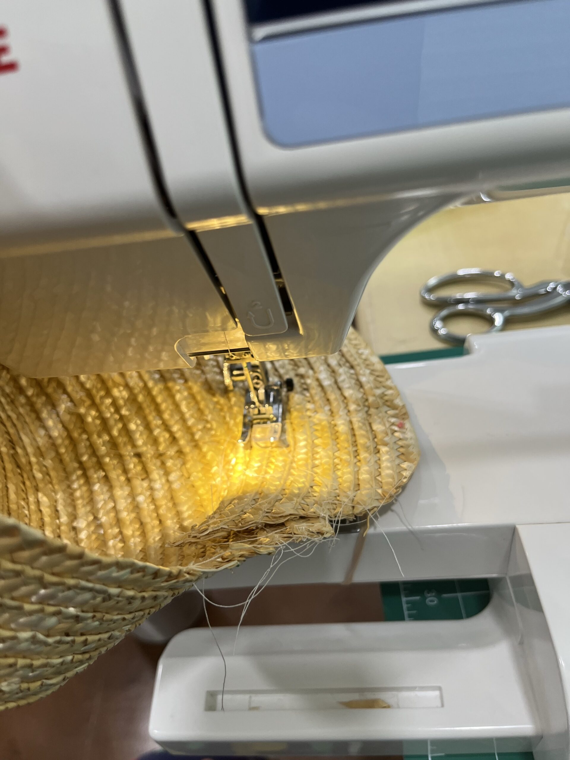 a straw hat being stitched on a sewing machine