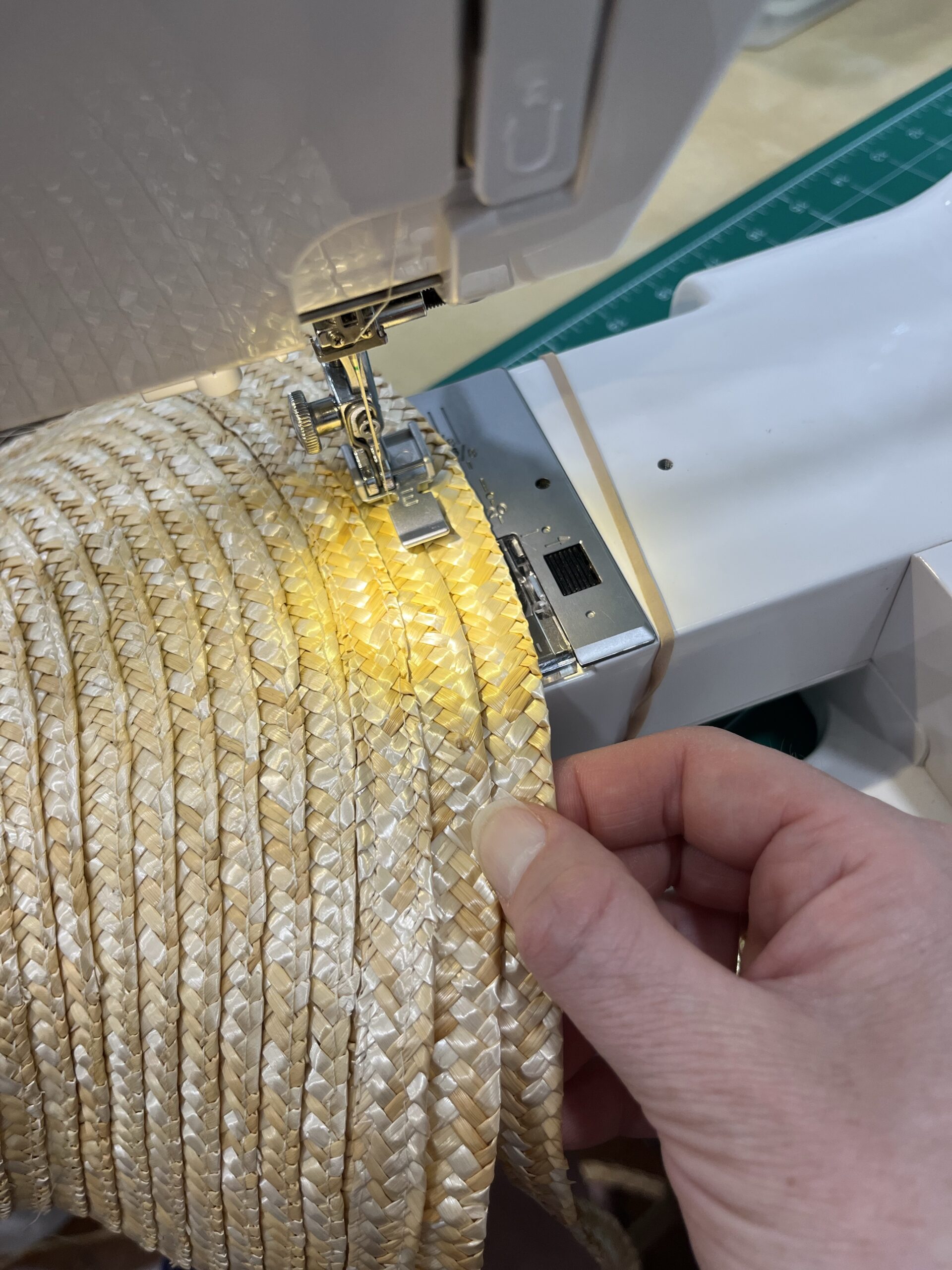 a single row of straw braid being sewn to the edge of an experimental straw hat