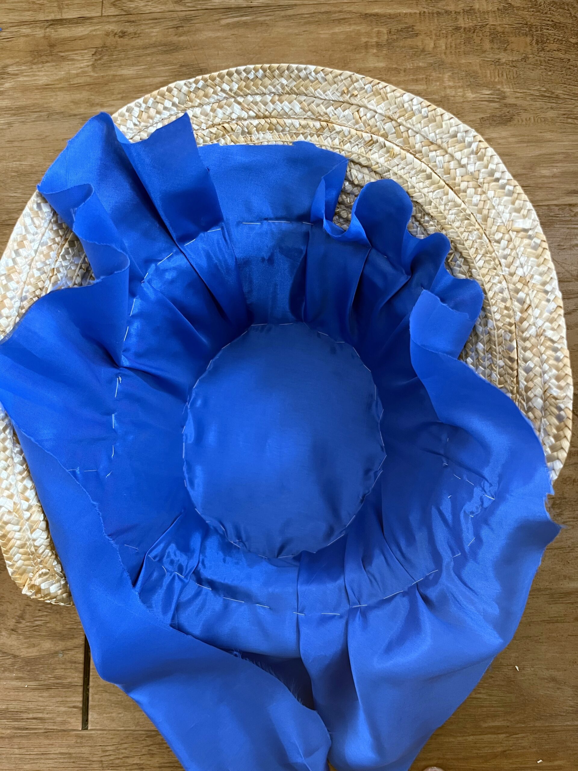 blue bemsilk fabric stitched down into the crown of a straw bonnet