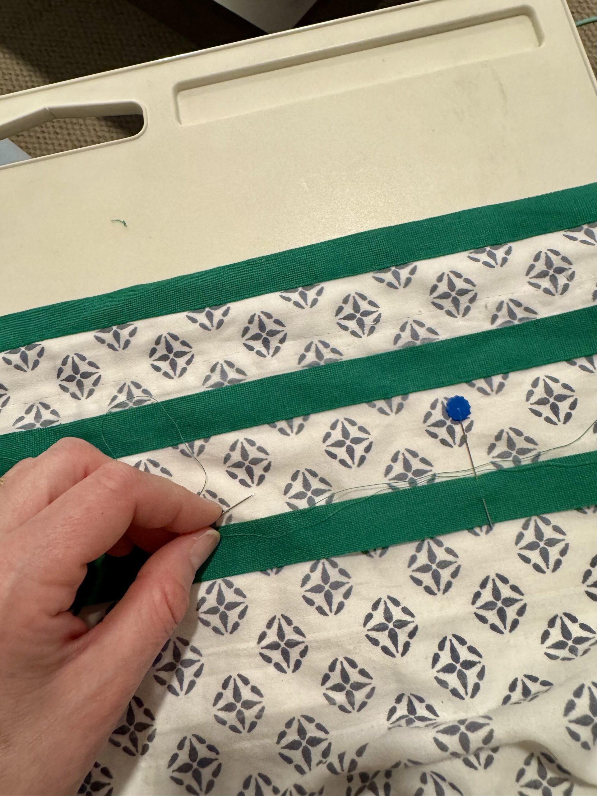 three rowns of racing stripes in emerald green cotton tape being stitched onto block printed fabric