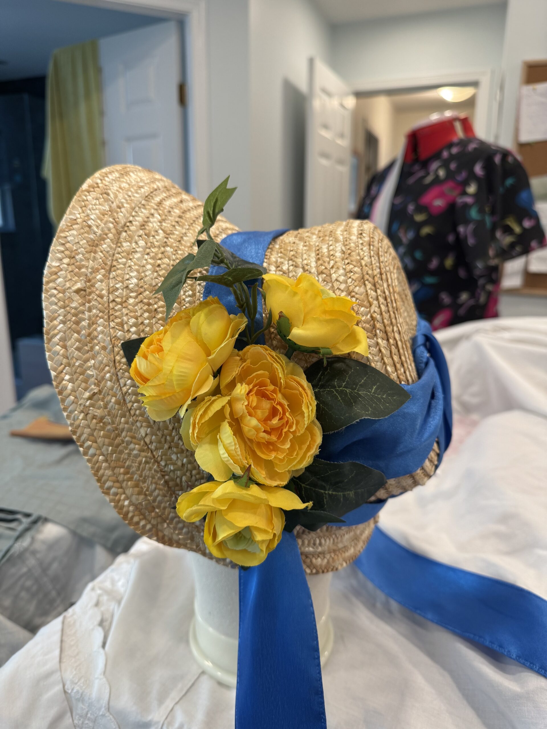 an experimental straw bonnet with a large cluster of yellow flowers attached to the right side